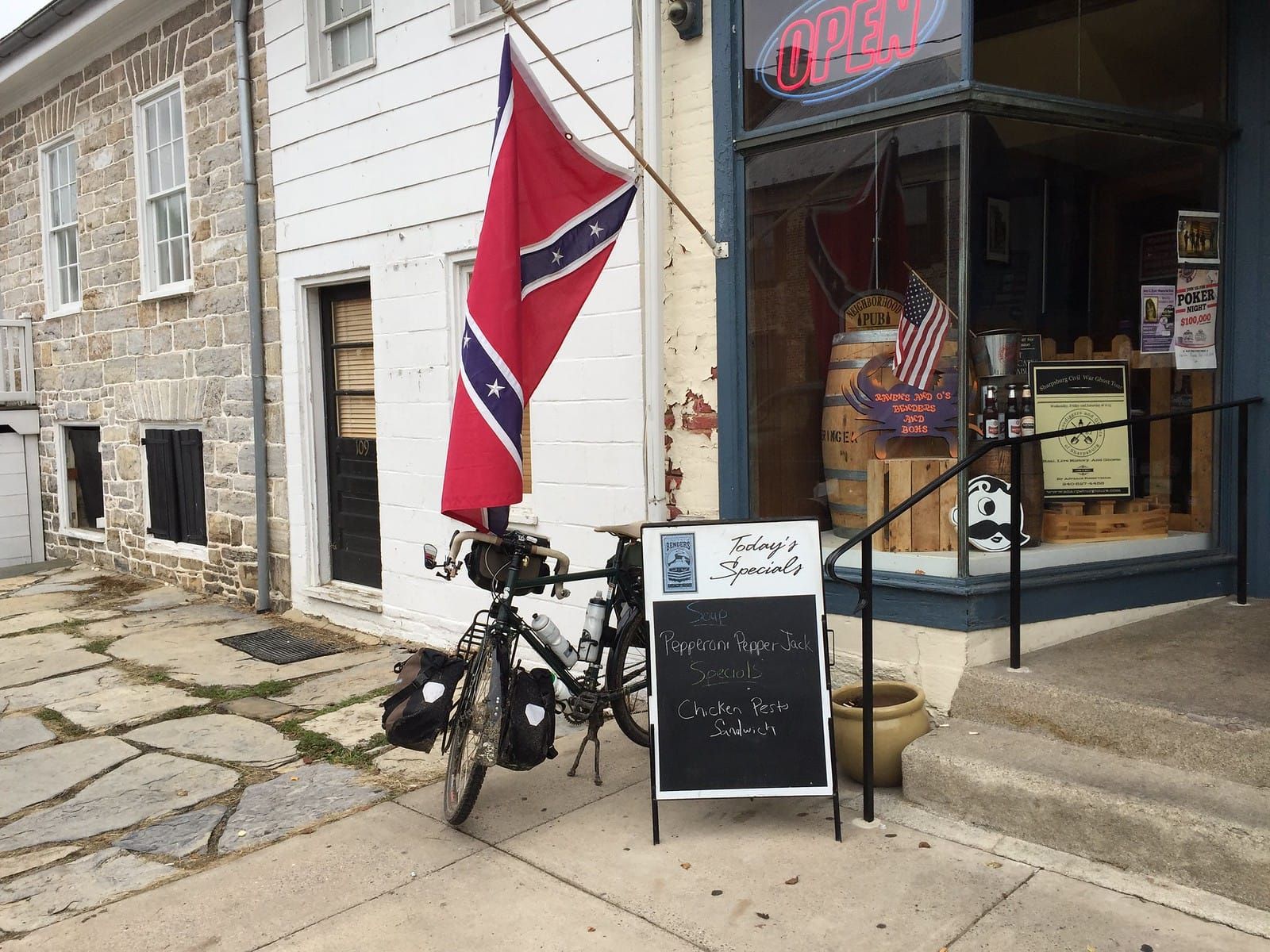Tank bicycle on her kickstand with the confederate flag flying from the building loud and proud.
