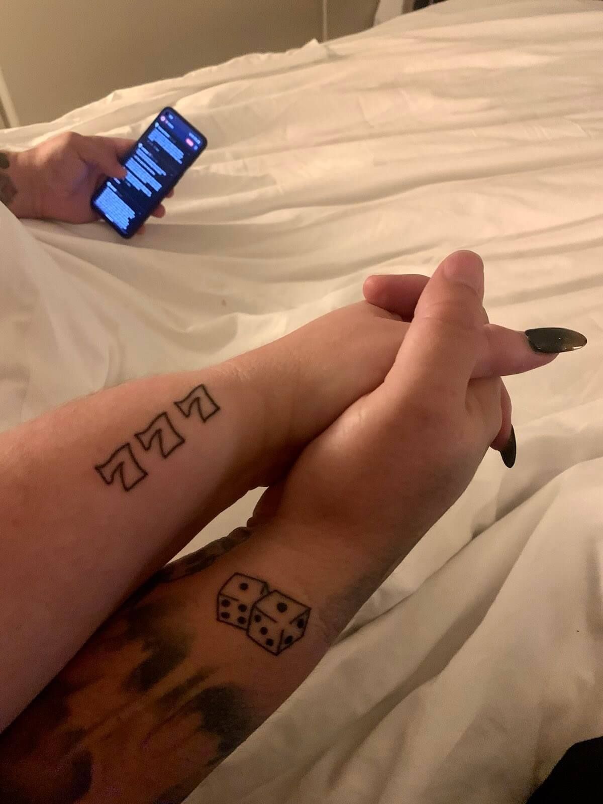 Mike and Rachelle holding hands, showing a dice and triple 7 tattoos.