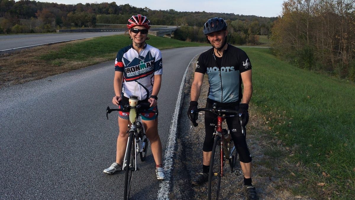 Kelly and her friend Scott standing on the road side with their bicycles.