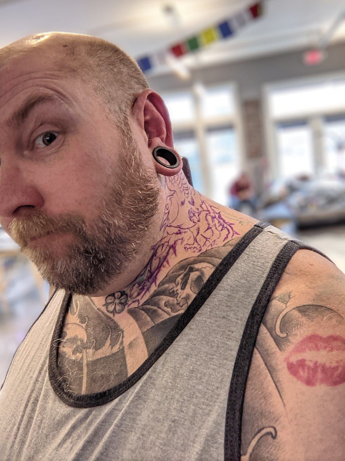 Mike looking at the camera, eye brow raised with the stensil of a new tattoo on his neck.