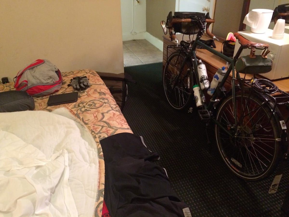 Unloaded touring bicycle, leaning against a desk in a motel room.