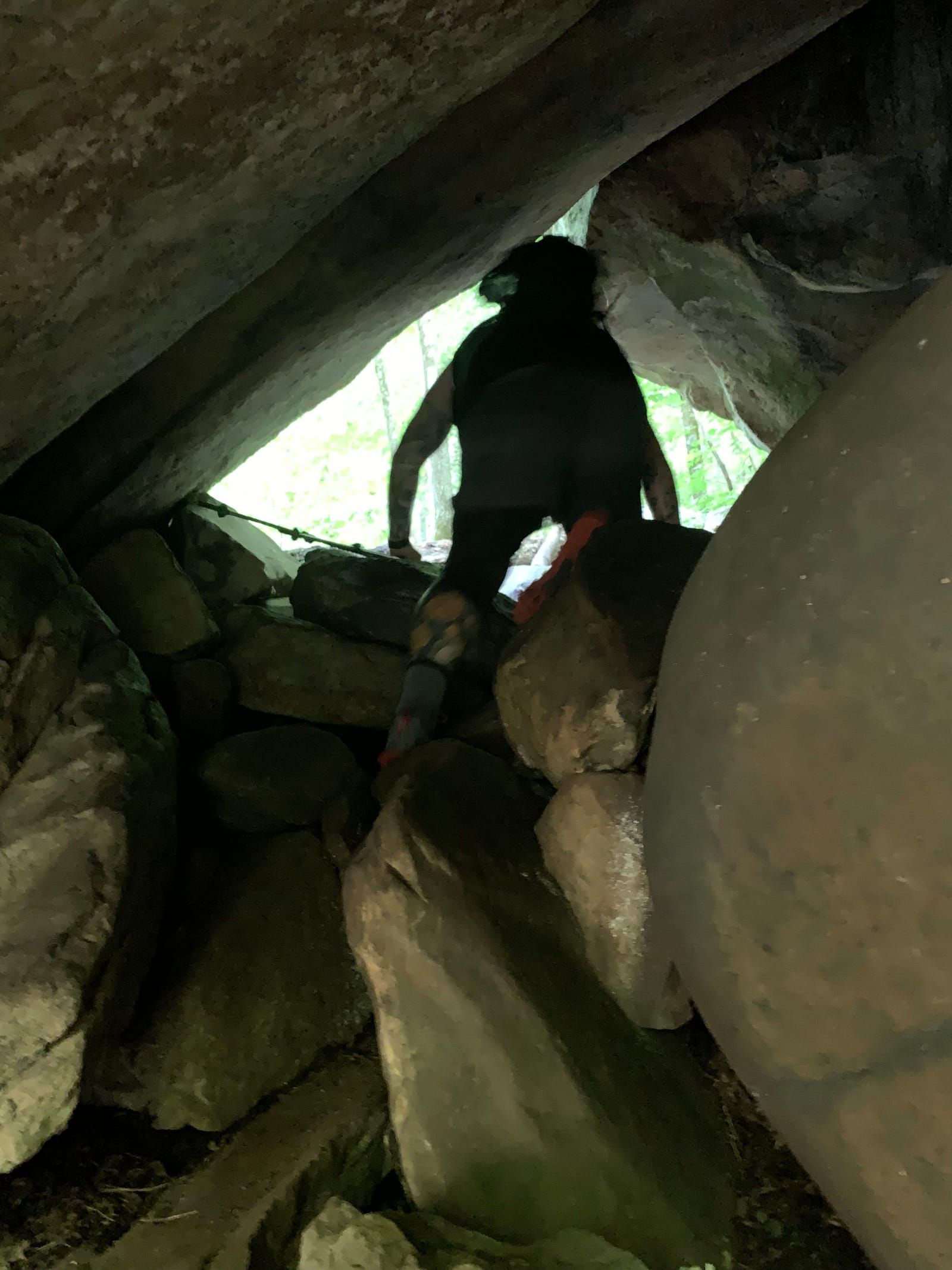 Photo of Mike from behind, climbing through a narrow opening between rocks.