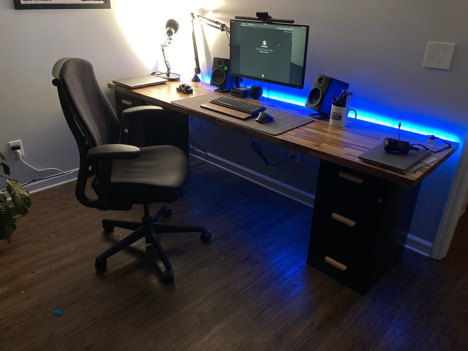 A wooden desk with neat cable management and RGB lights glowing.