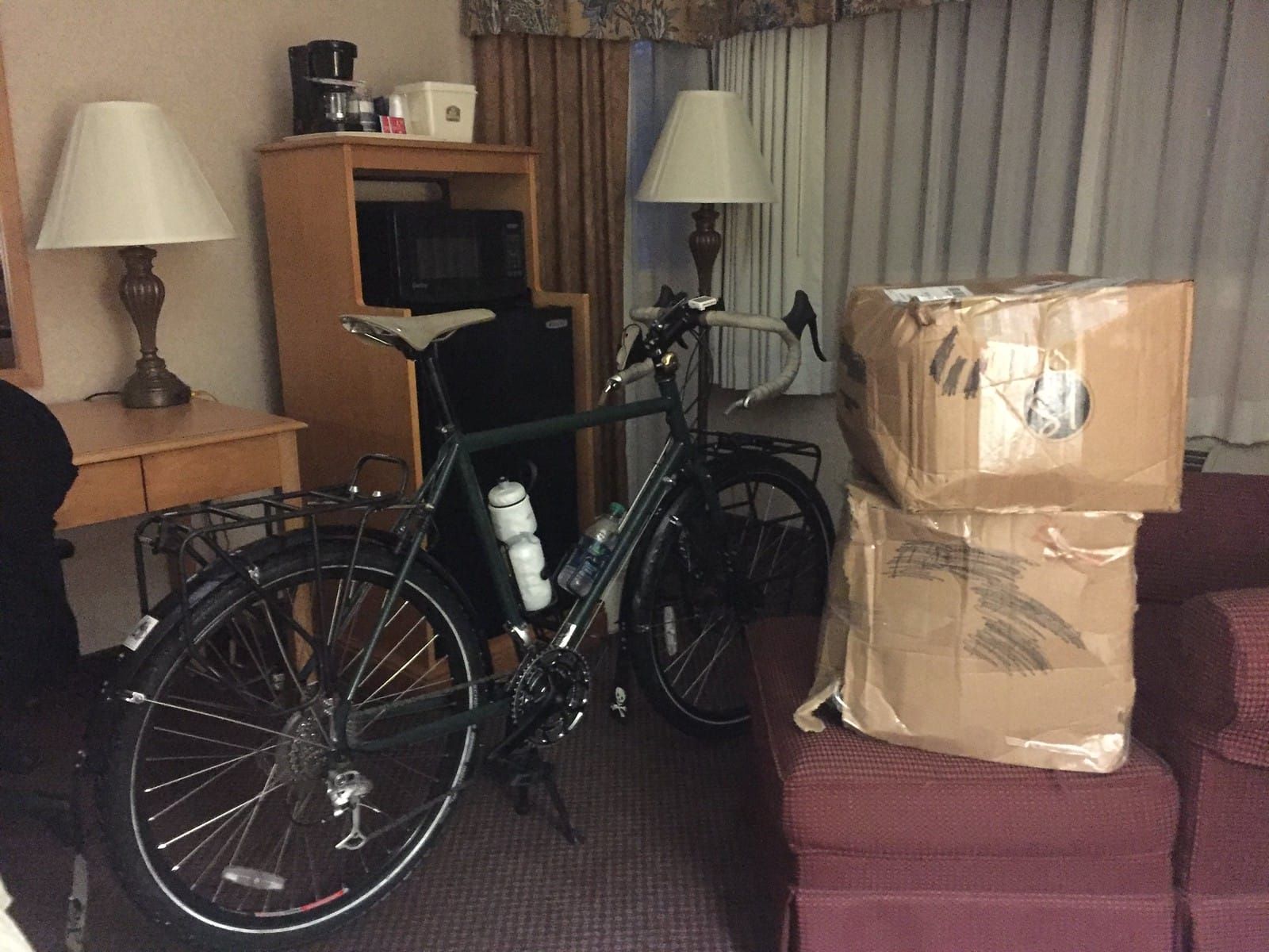 Tank bicycle in the motel room with boxes of camping gear stacked nearby.