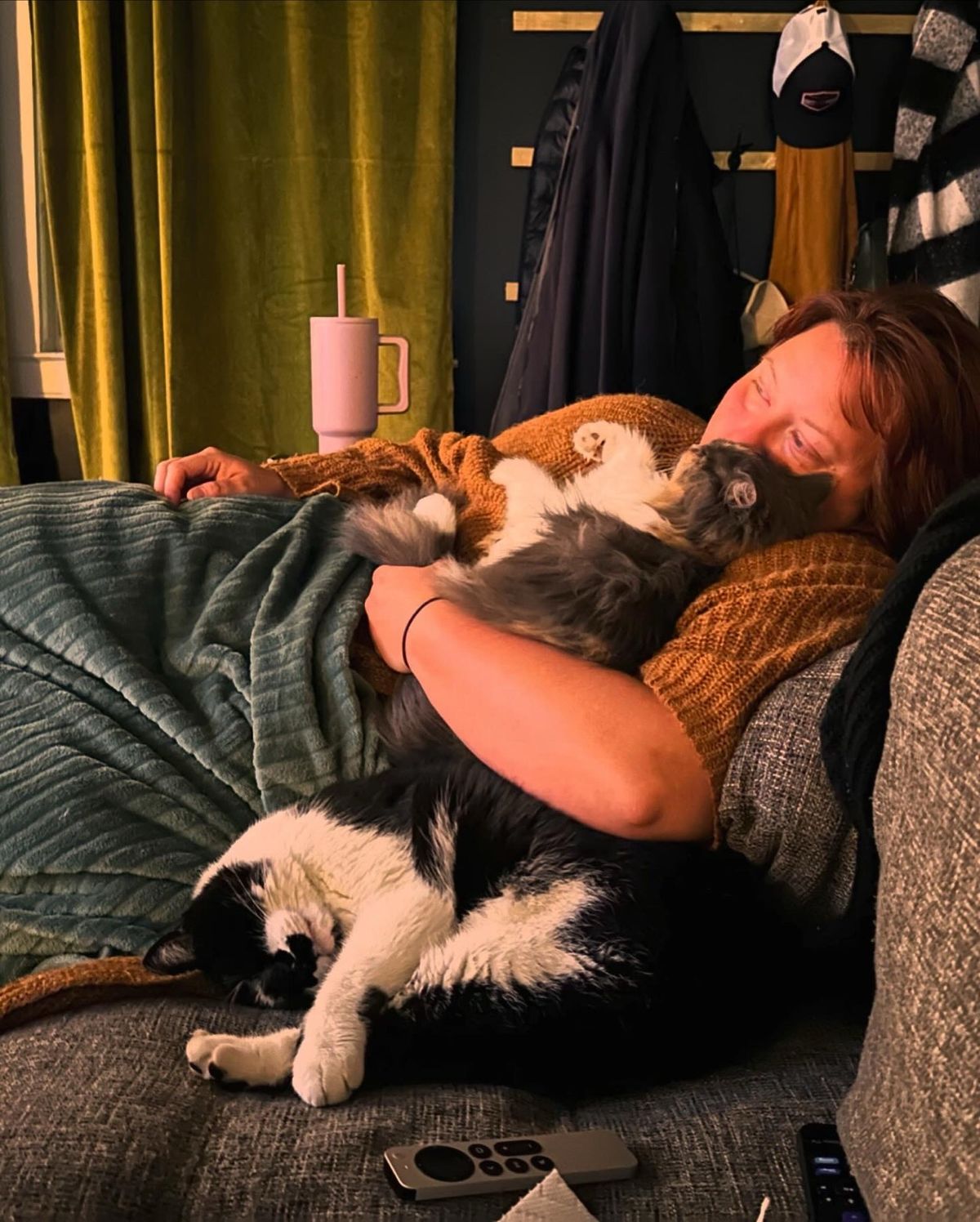 Rachelle on the couch holding Polly belly-up while Linus sleeps beside them