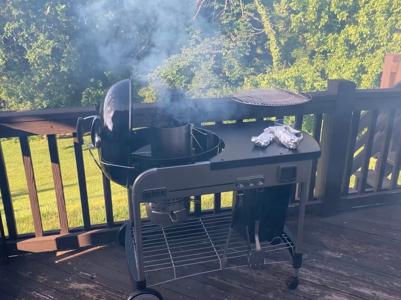 Charcoal grill with the charcoal smoking and getting ready. Some grille corn is ready to be placed onto the grill.