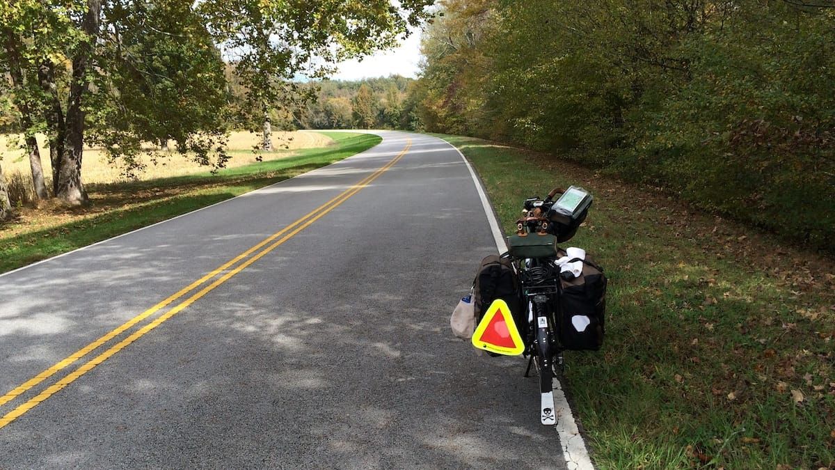 Scenic view of the Natchez Trace going into the distance with a loaded touring bicycle in the foreground.