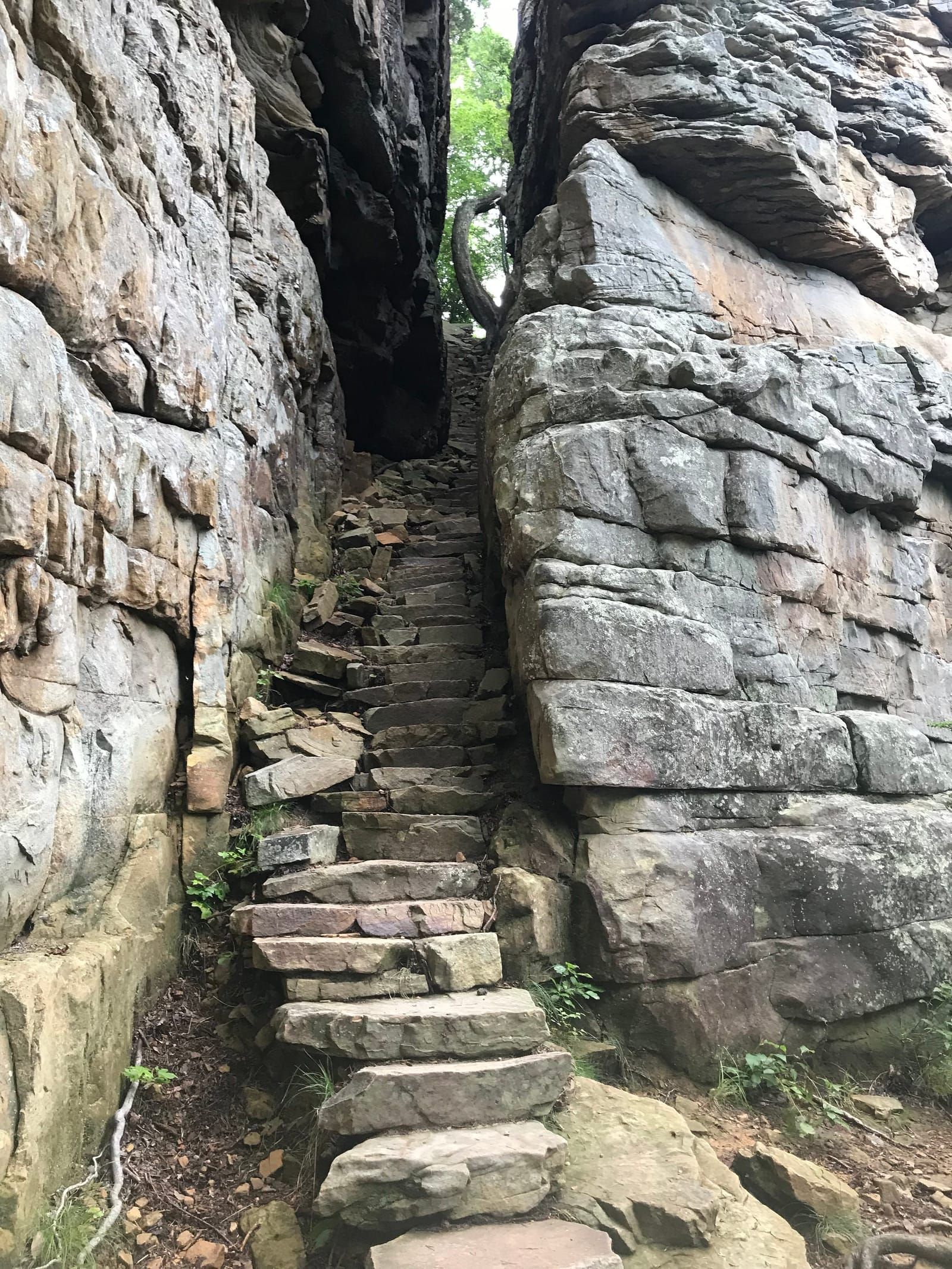 View from the bottom of Stone Door. Man made steps raising between two very large rocks in the cliff face.