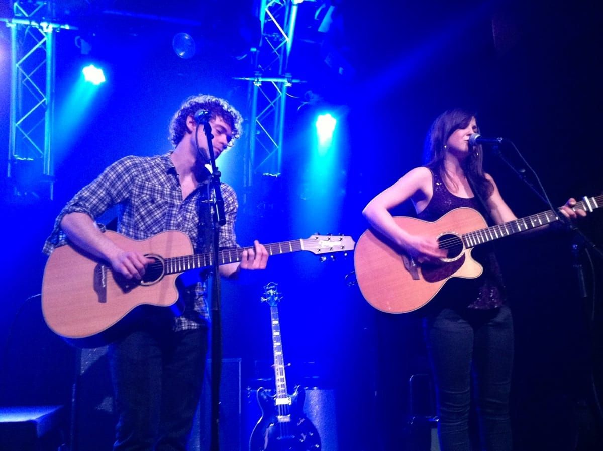 Striking Matches playing acoustic guitars on stage.
