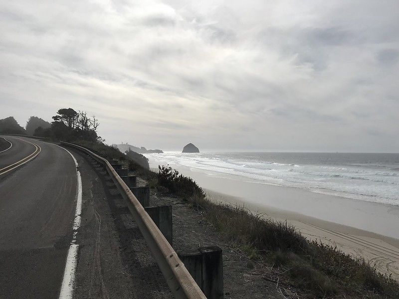 A large boulder in the distance on the beach.
