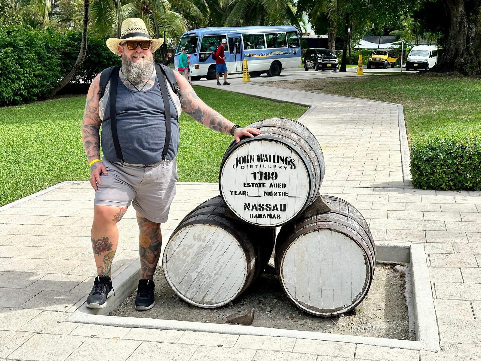 Michael poses next to a stack of three barrels. The top barrel has the John Watling's distrillery logo.