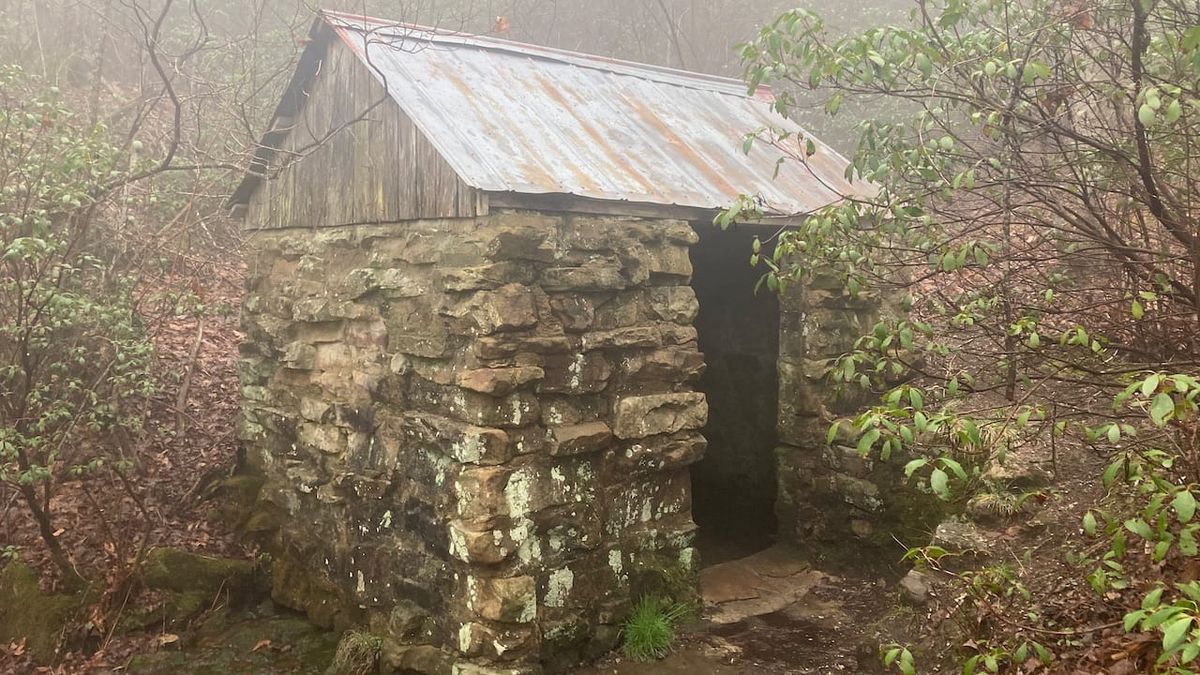 A small stone shed with a tin roof.