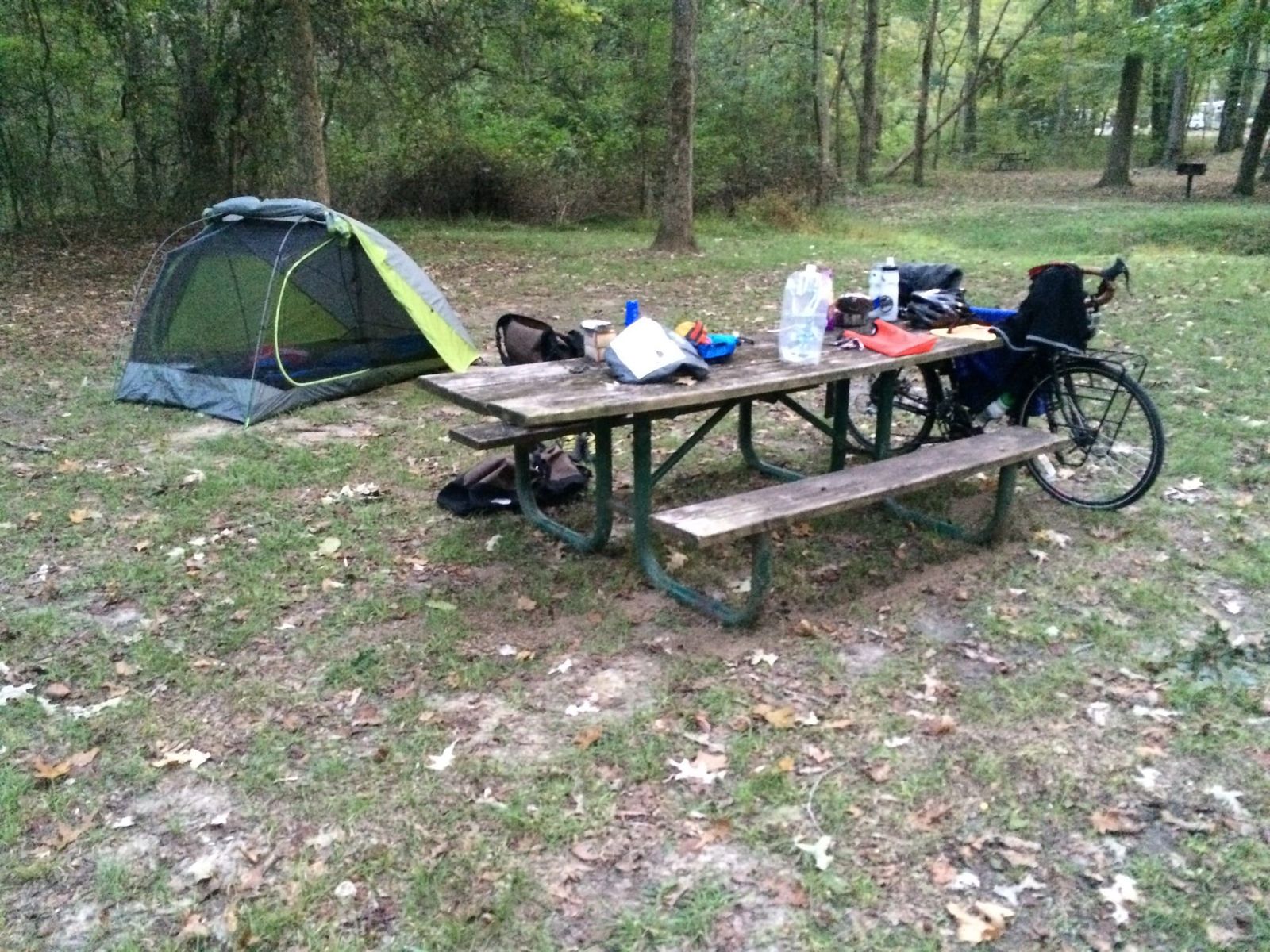 Primative camp ground with picnic table, and bicycle with a tent.