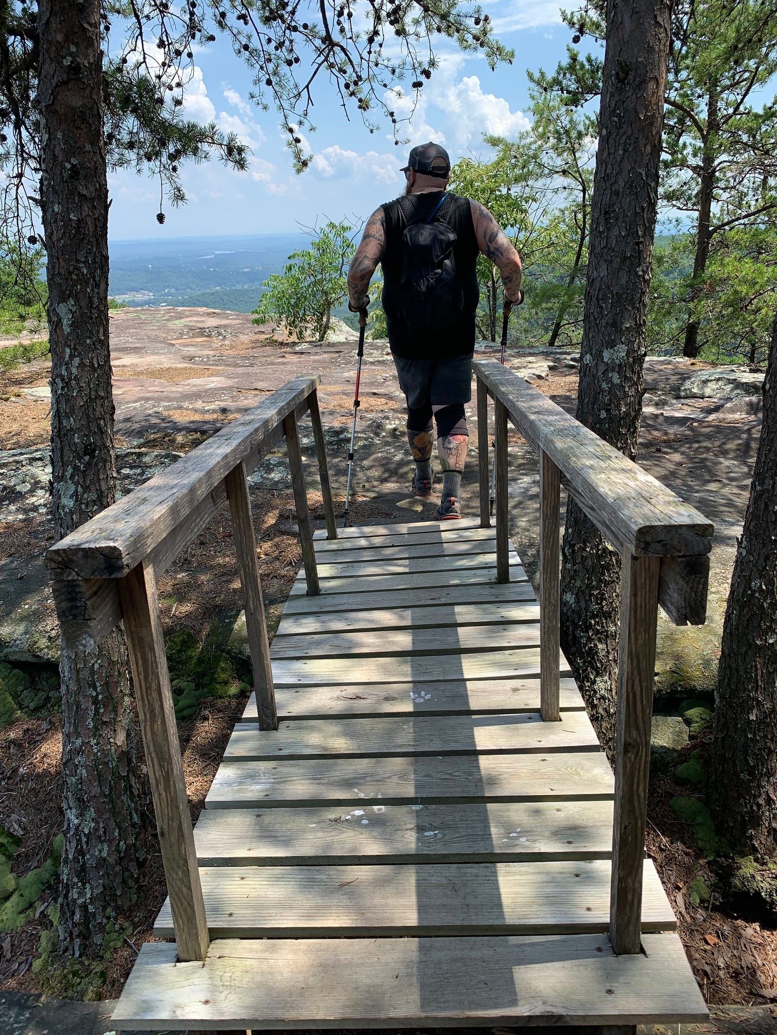 A photo of Mike from behind, hiking over a bridge and arriving at buzzard point.