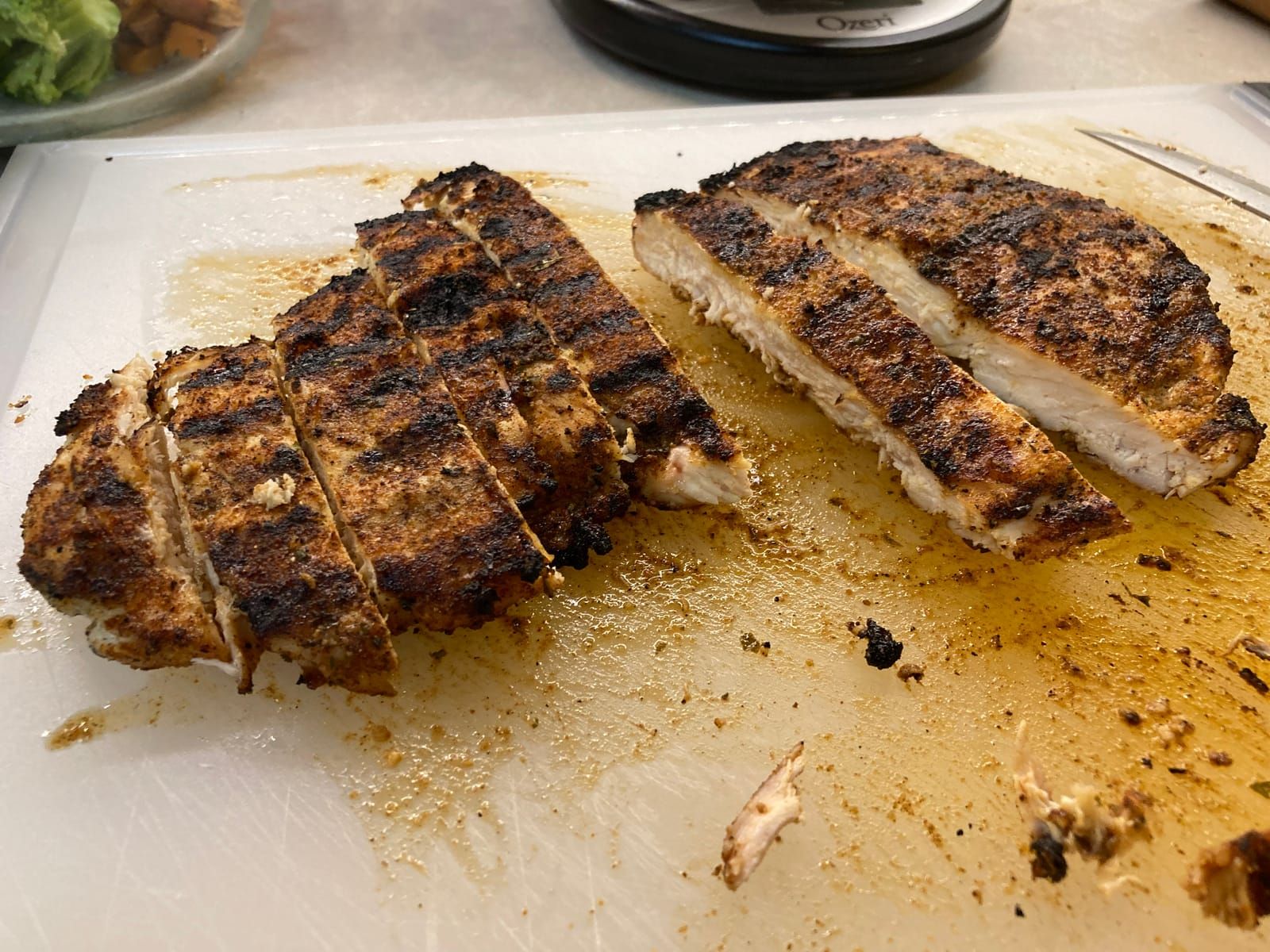 Grilled and juicy chicken breast, cut up on a cutting board ready for plating.