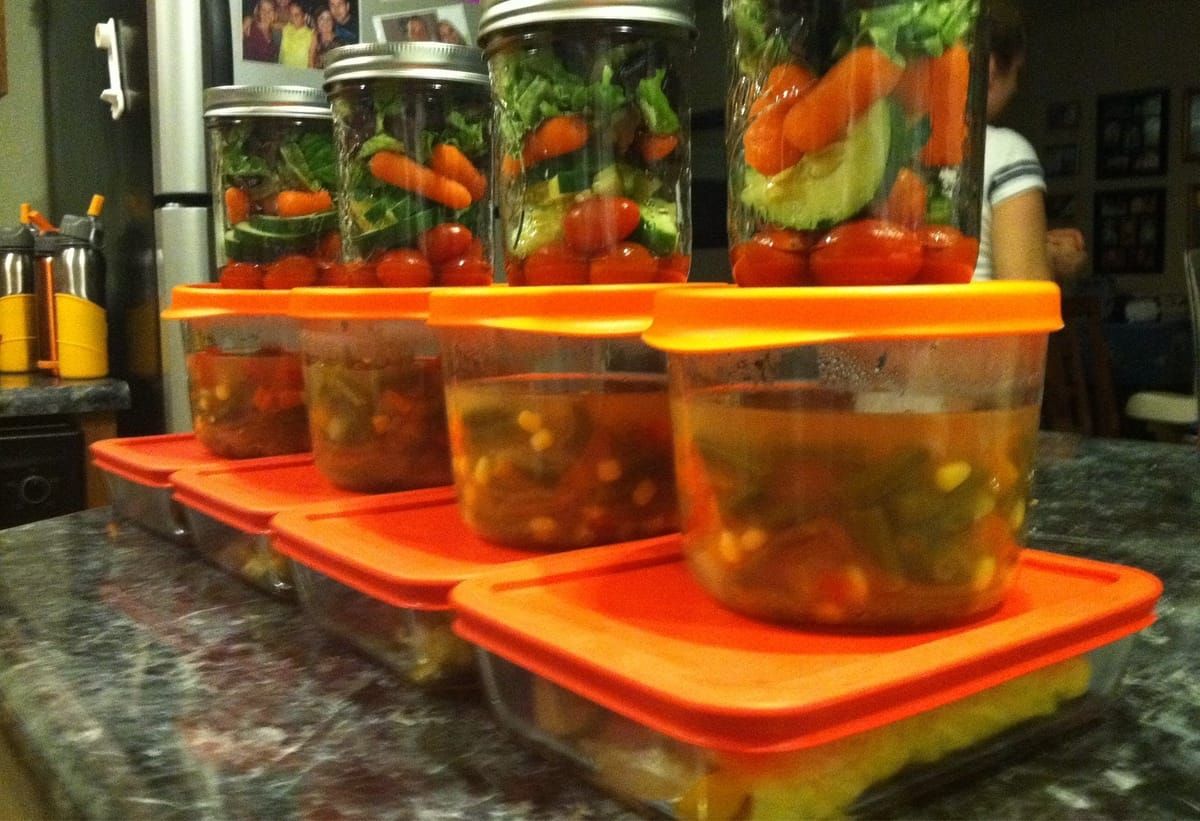 Glass containers lined up on the counter with food in them.