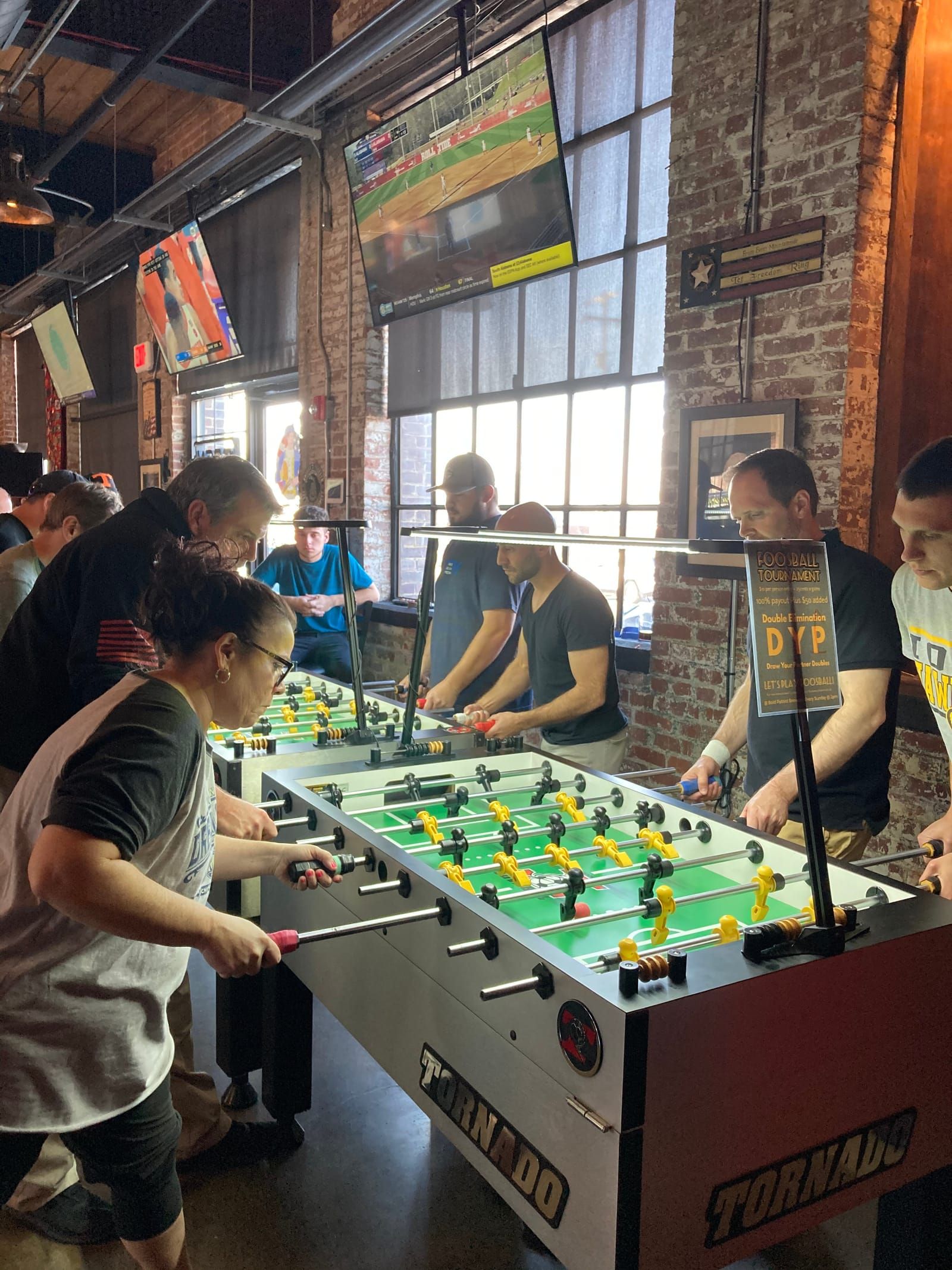 Players play foosball with intense expressions on their faces.