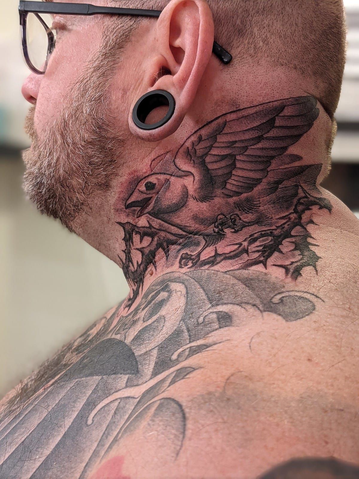 Photo of Mike from the side, showing a bird tattoo on his neck.