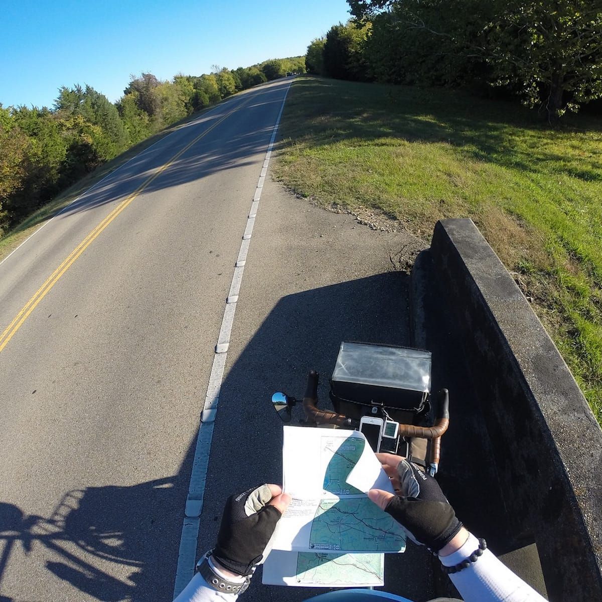 Standing roadside, stradling the bicycle changing a map panel. POV. 