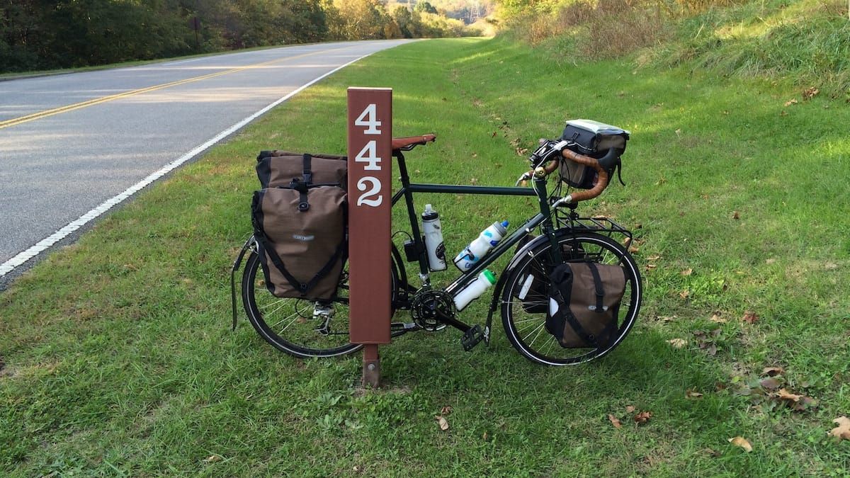 Loaded touring bicycle leaning against mile marker 442 of the Natchez Trace.
