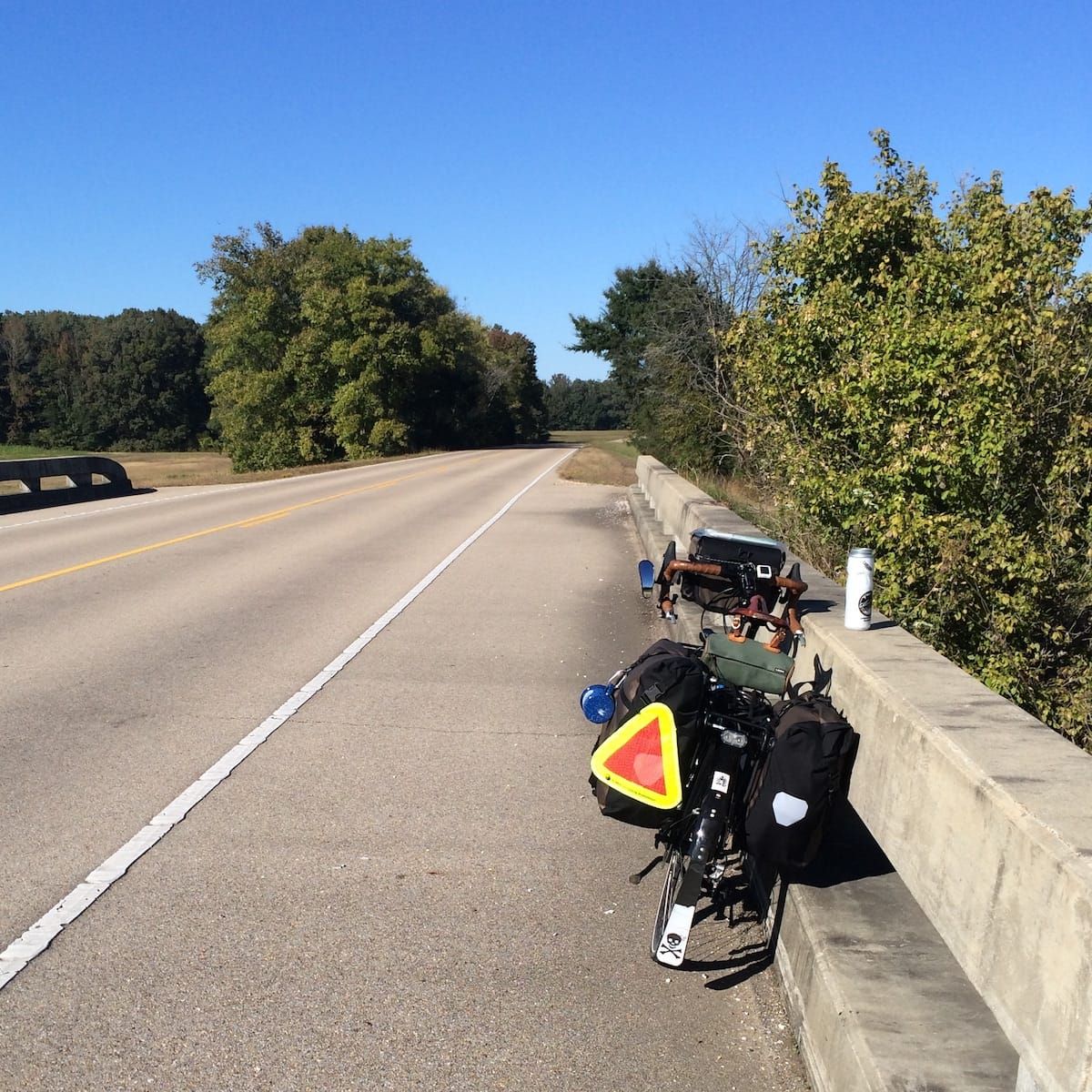 Loaded touring bicycle leaning against a bridge over pass.