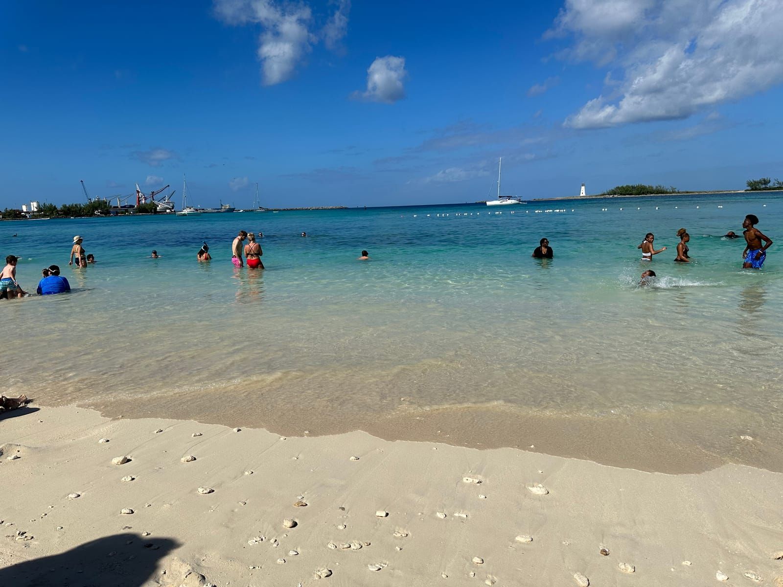White sandy beach and clear water. People are enjoying the water.