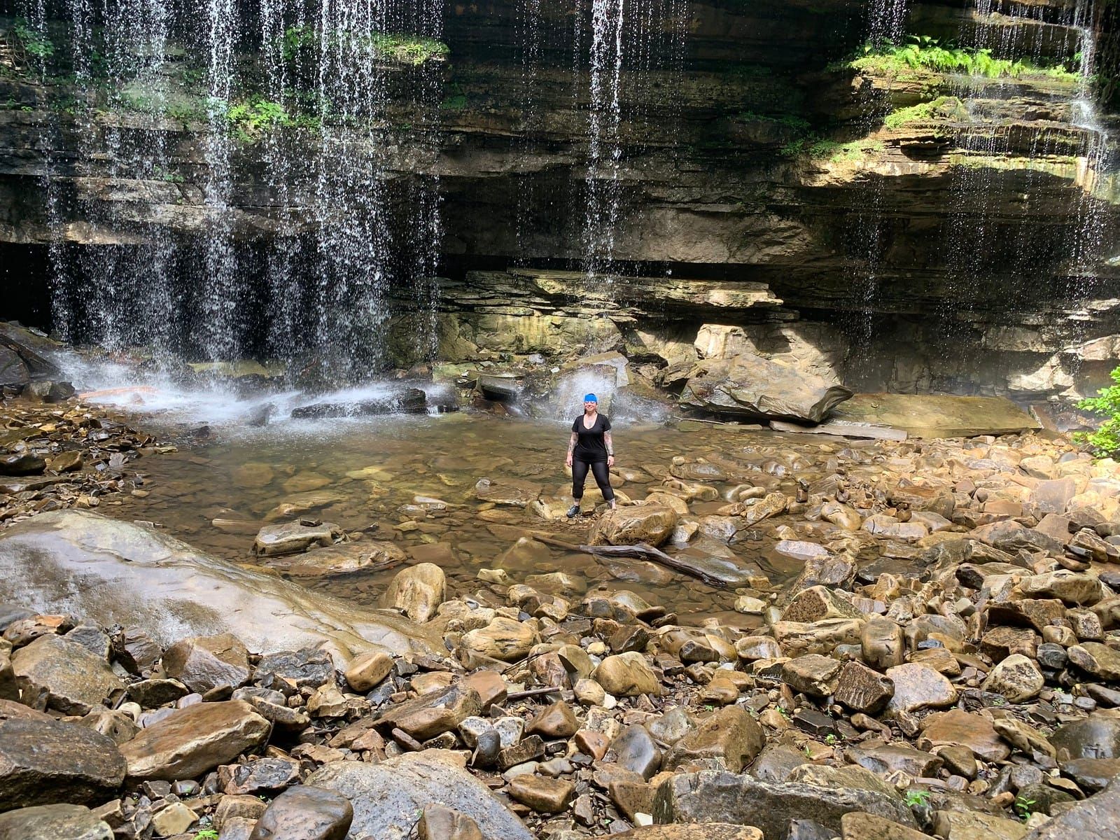 Meredith posing with the waterfall in the background and a blue bandana on her head.