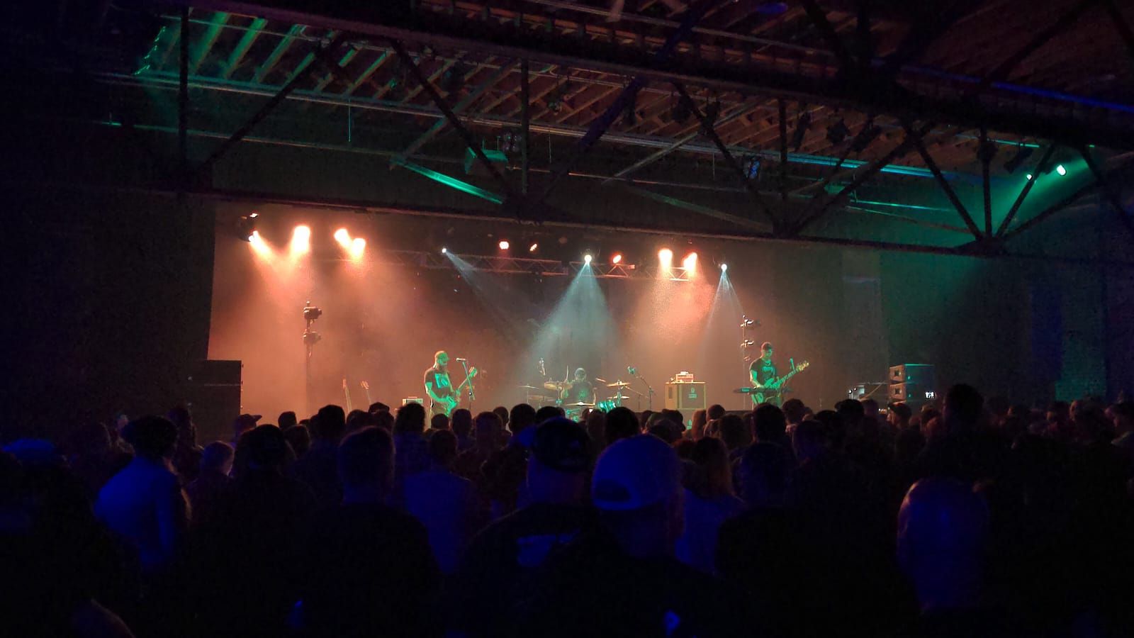 A metal band plays on a stage in dimly lit venue.