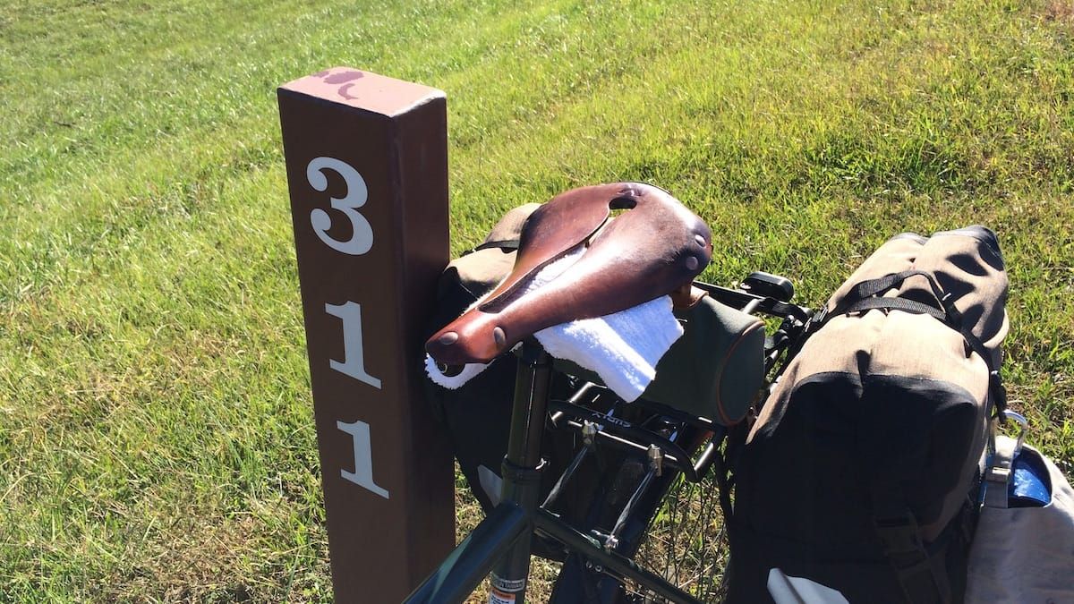 Broken leather bicycle seat with towels jammed underneath to provide some cushion.