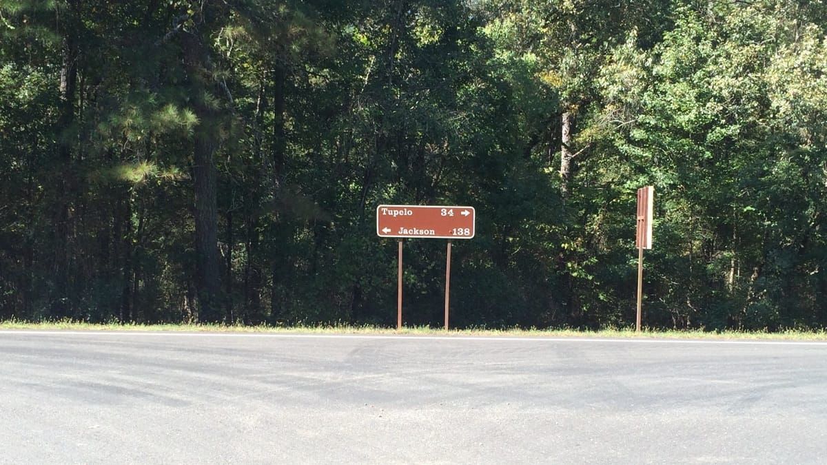 Road sign. Right, 34 miles to Tupelo. Left, 138 miles to Jackson.