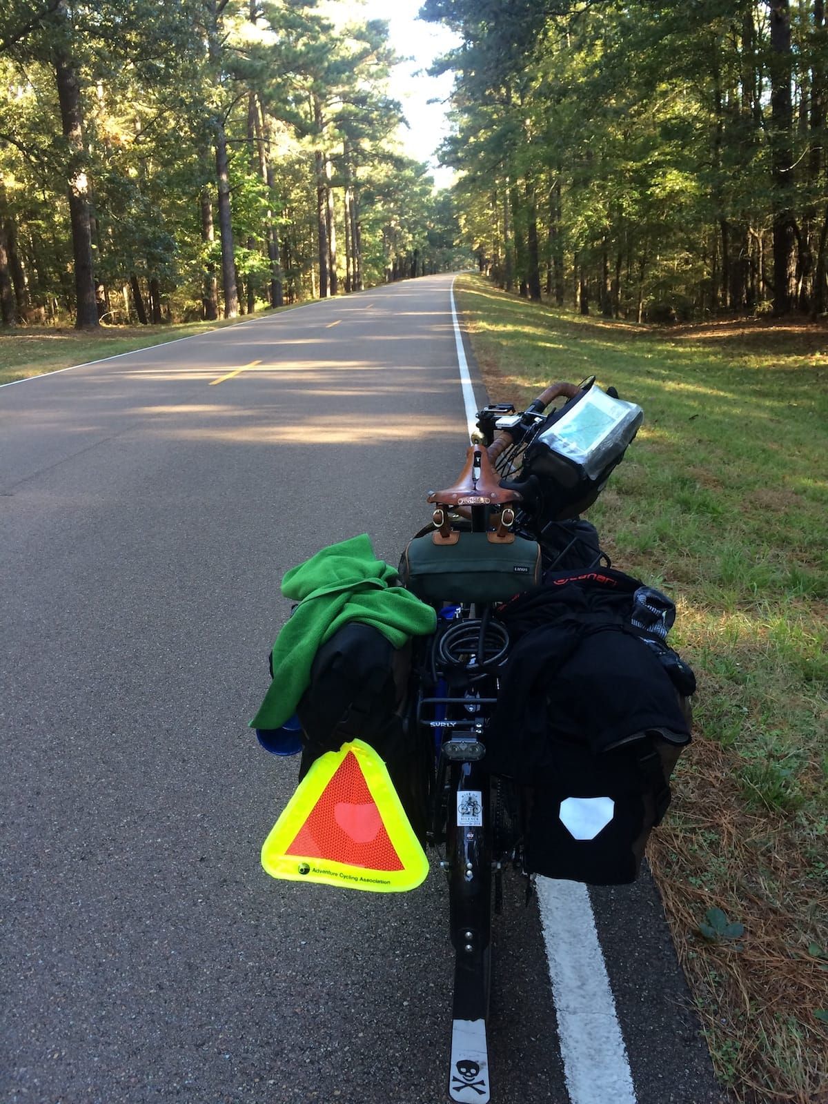 Loaded touring bicyle parked on the side of the road with the road stretching out ahead.