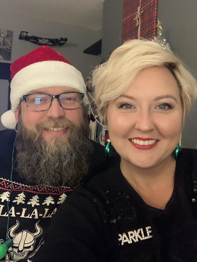Mike and Rachelle selfie. Mike wears a santa hat and ugly sweater. Rachelle wearing black sparkle top.