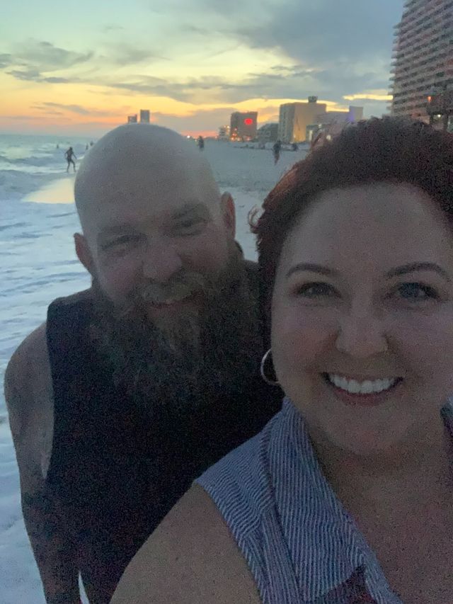 Mike and Rachelle selfie on the beach with the evening sun in the background.