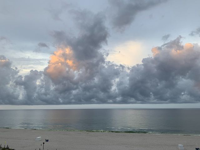 Morning photo of an empty beach from the condo balcony. Low heavy clouds are in the middle distance.