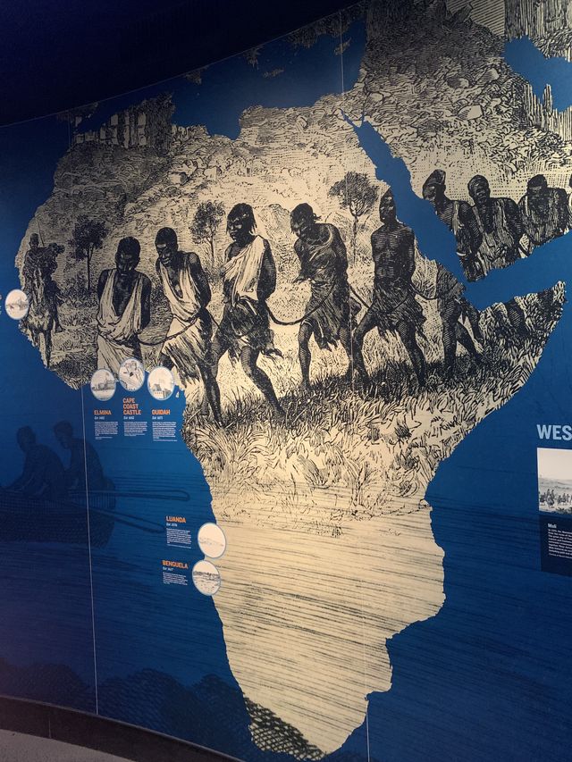 Wall sized display of the continent of Africa depicting slaves, bound and walking across the map..