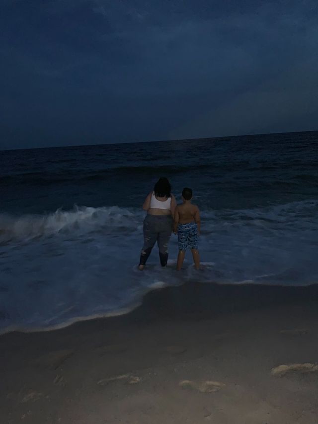 Mom Jessica and 10 year old Carter standing in the late evening surf facing the ocean.