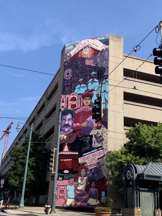 Painted street mural on the side of a parking garage. The mural is 4 stories high is a scene of memphis and it's people.