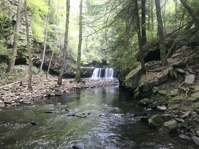 Stream in the foreground with a small waterfall and pool in the distance.